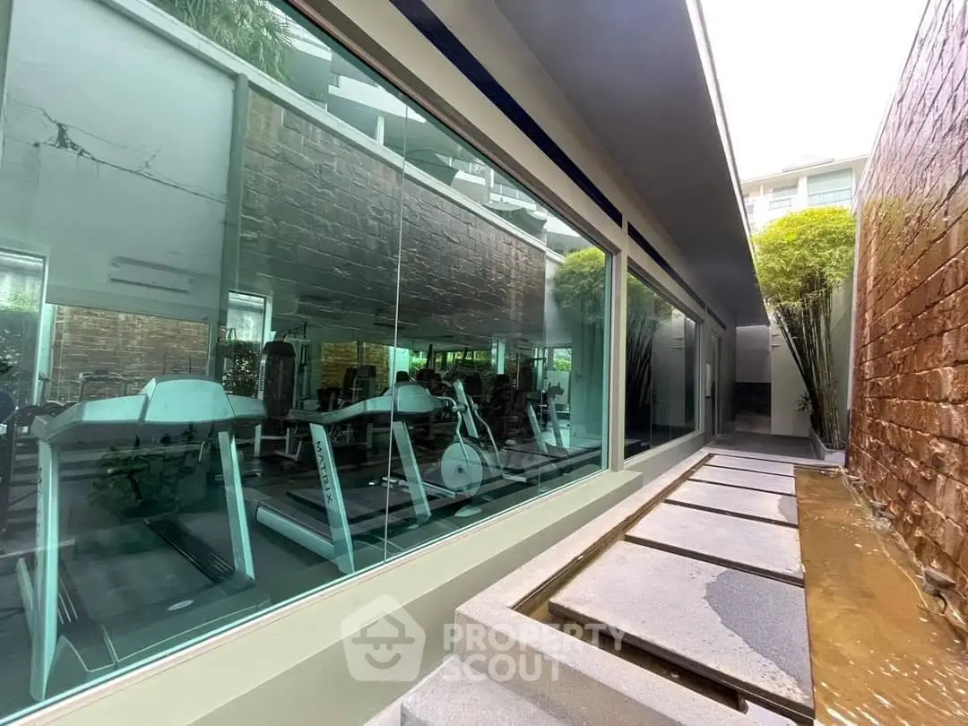 Modern gym with large windows and sleek design in a luxury residential building.