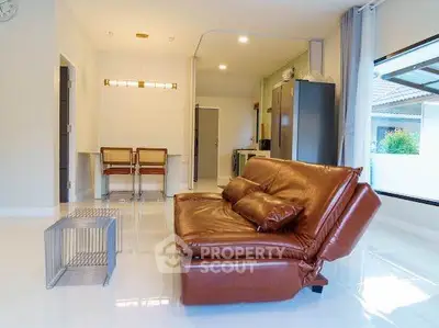 Modern living room with sleek leather sofa and open layout, featuring stylish dining area and bright natural light.