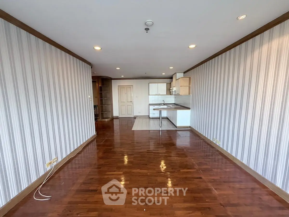 Spacious open-plan living room with wooden flooring and modern kitchen