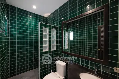 Stylish green-tiled bathroom with modern fixtures and large mirror