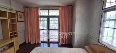 Cozy bedroom with large window and soft pink curtains, perfect for natural light lovers.