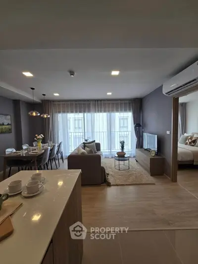 Modern open-plan living room with dining area and cozy bedroom view.