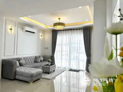 Elegant living room with luxurious sofa and chandelier, featuring large windows and modern decor.