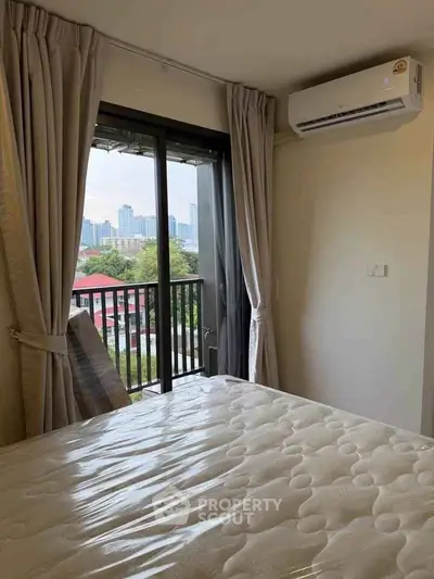Cozy bedroom with balcony view in modern apartment, featuring air conditioning and natural light.
