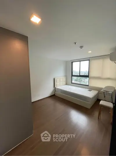 Spacious bedroom with large window offering city views, featuring a single bed and modern furnishings.