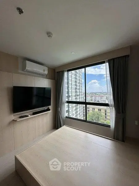 Modern living room with large window offering stunning city view, featuring sleek TV setup and minimalist design.