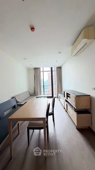 Spacious living room with modern furniture and large window offering city views.