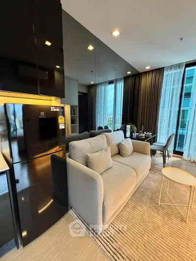 Modern living room with sleek black fridge and cozy sofa in a high-rise apartment.