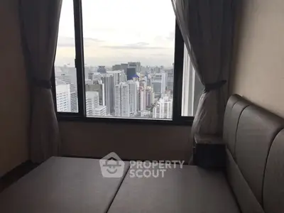 High-rise bedroom with stunning cityscape view through large window.