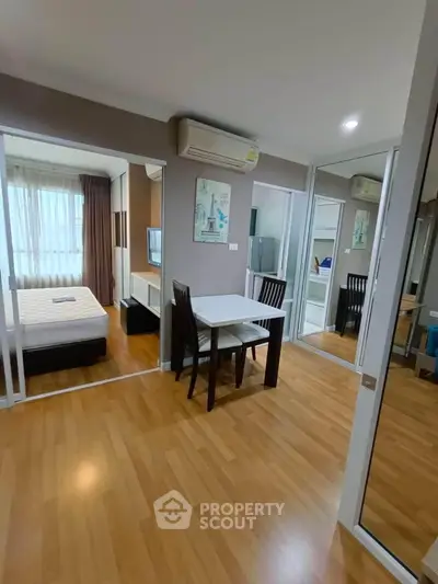 Modern apartment interior with wooden flooring, dining area, and bedroom view.