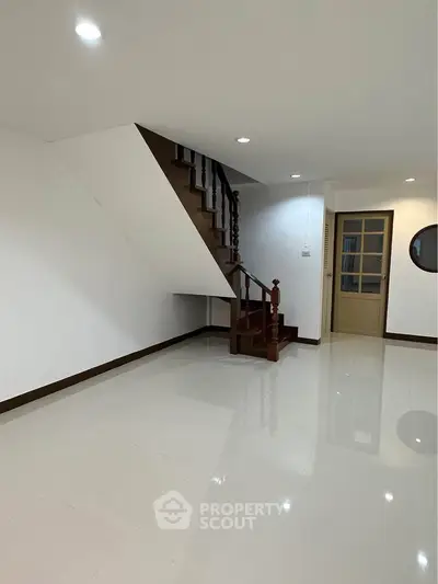 Spacious interior with elegant staircase and glossy tiled flooring, perfect for modern living.