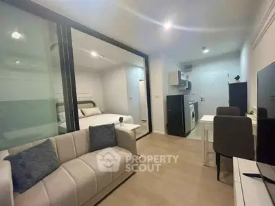 Modern open-plan living room with sleek kitchen and cozy bedroom in a stylish apartment.