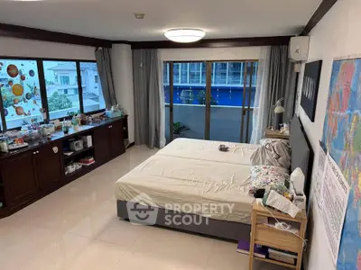 Spacious bedroom with large windows and modern decor in a well-lit apartment.