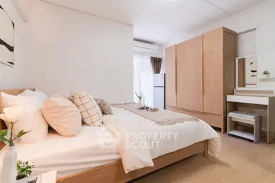 Cozy bedroom with modern decor, featuring a comfortable bed, wooden wardrobe, and natural light.
