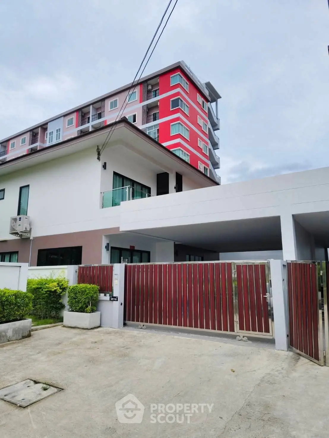 Modern multi-story building with gated entrance and lush greenery