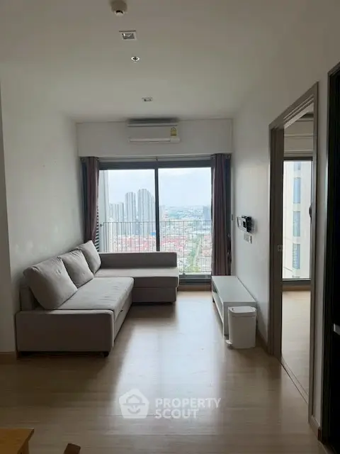 Modern living room with city view, featuring a stylish sofa and large window for natural light.