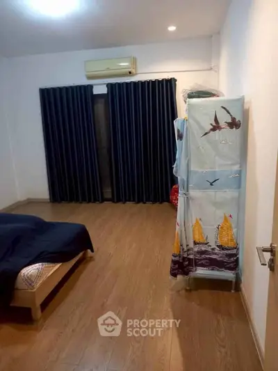Spacious bedroom with wooden flooring and air conditioning, featuring a unique wardrobe cover design.