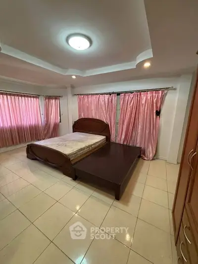 Spacious bedroom with elegant pink curtains and stylish ceiling design