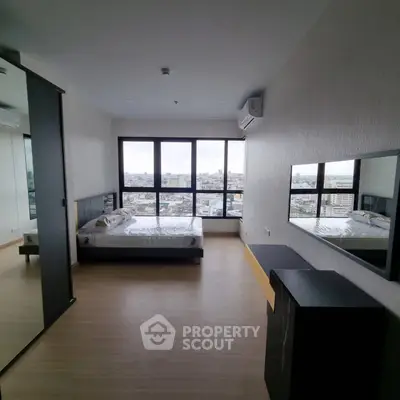 Spacious bedroom with large windows offering stunning city views