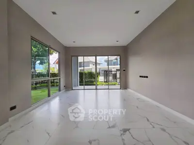 Spacious empty room with large windows and marble flooring in modern home.