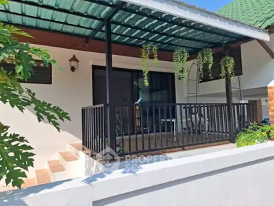 Charming house with covered patio and lush greenery, perfect for outdoor relaxation.