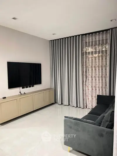 Modern living room with sleek TV setup and elegant curtains