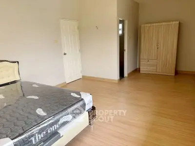 Spacious bedroom with wooden flooring and modern furniture