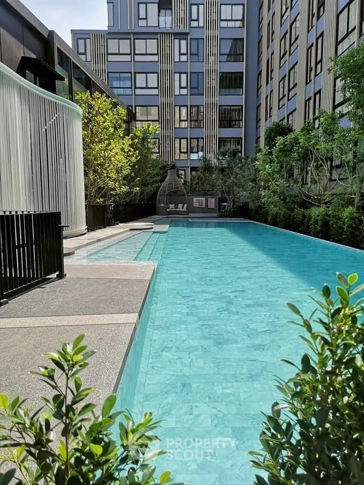 Luxurious modern apartment complex with stunning outdoor pool and lush greenery.
