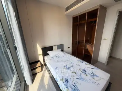 Modern bedroom with large window and built-in wardrobe in a high-rise apartment.
