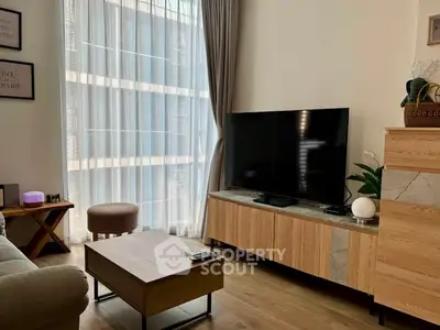 Modern living room with large TV, stylish furniture, and floor-to-ceiling window.