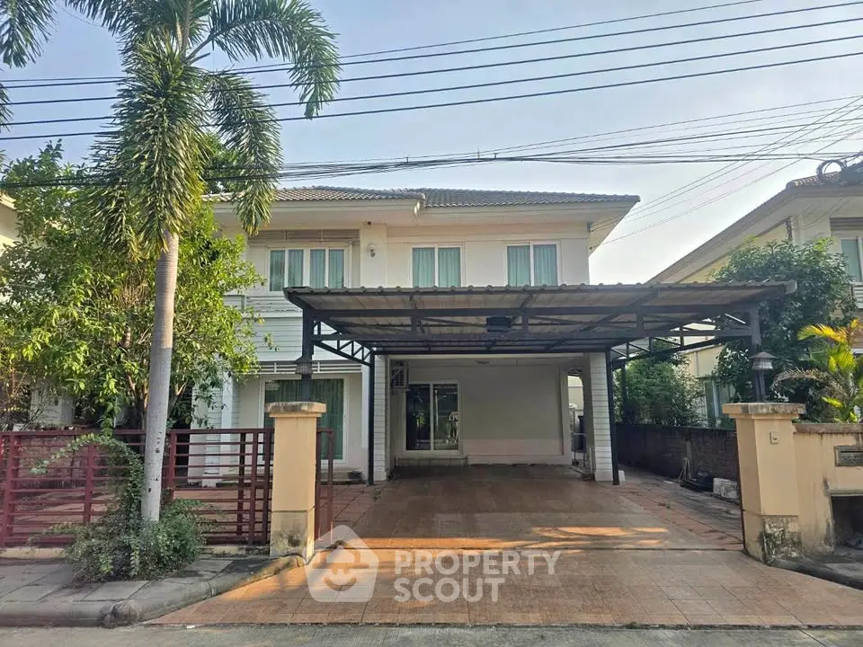 Charming two-story house with spacious carport and lush greenery in a serene neighborhood.