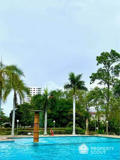 Luxurious outdoor pool surrounded by lush greenery and palm trees, perfect for relaxation and leisure.