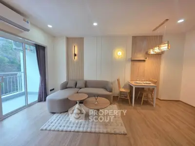 Modern living room with stylish furniture and balcony access, featuring elegant lighting and wooden flooring.