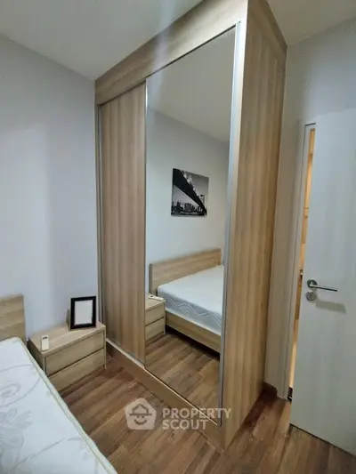 Modern bedroom with wooden flooring and mirrored wardrobe