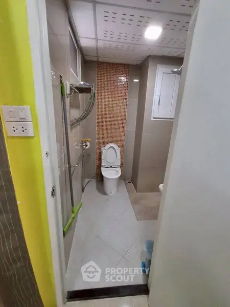 Compact bathroom with modern fixtures and tiled walls in a cozy apartment.