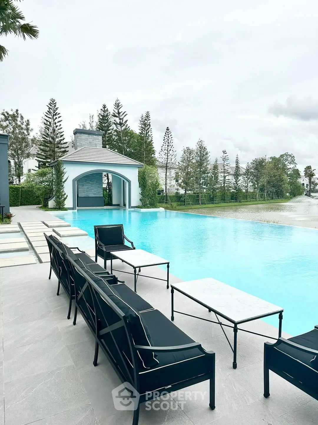 Luxurious outdoor pool area with elegant seating and lush greenery, perfect for relaxation and entertainment.