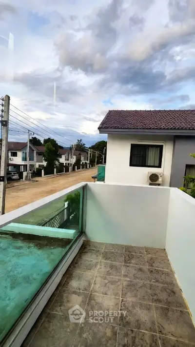 Charming balcony view with modern glass railing overlooking suburban neighborhood.