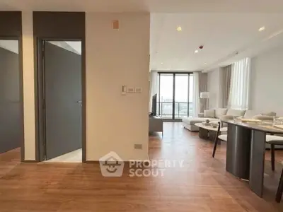 Spacious modern living room with wooden flooring and large windows offering natural light.