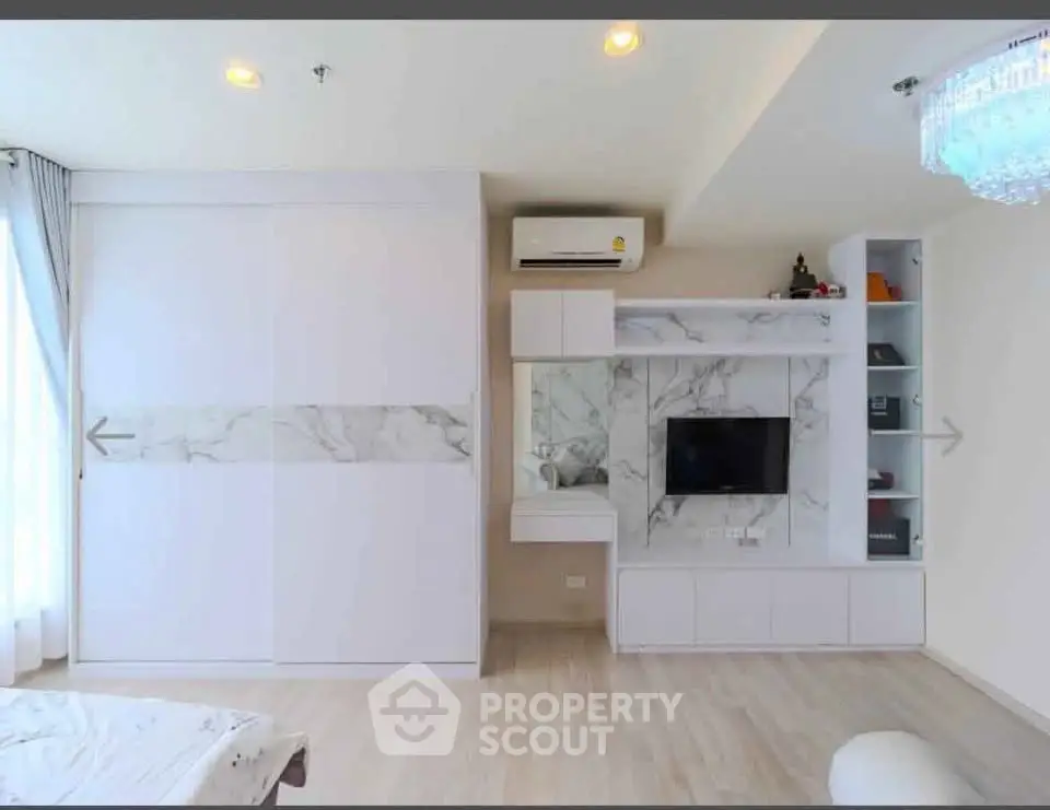 Modern living room with built-in TV unit and air conditioning, featuring elegant marble accents and ample natural light.