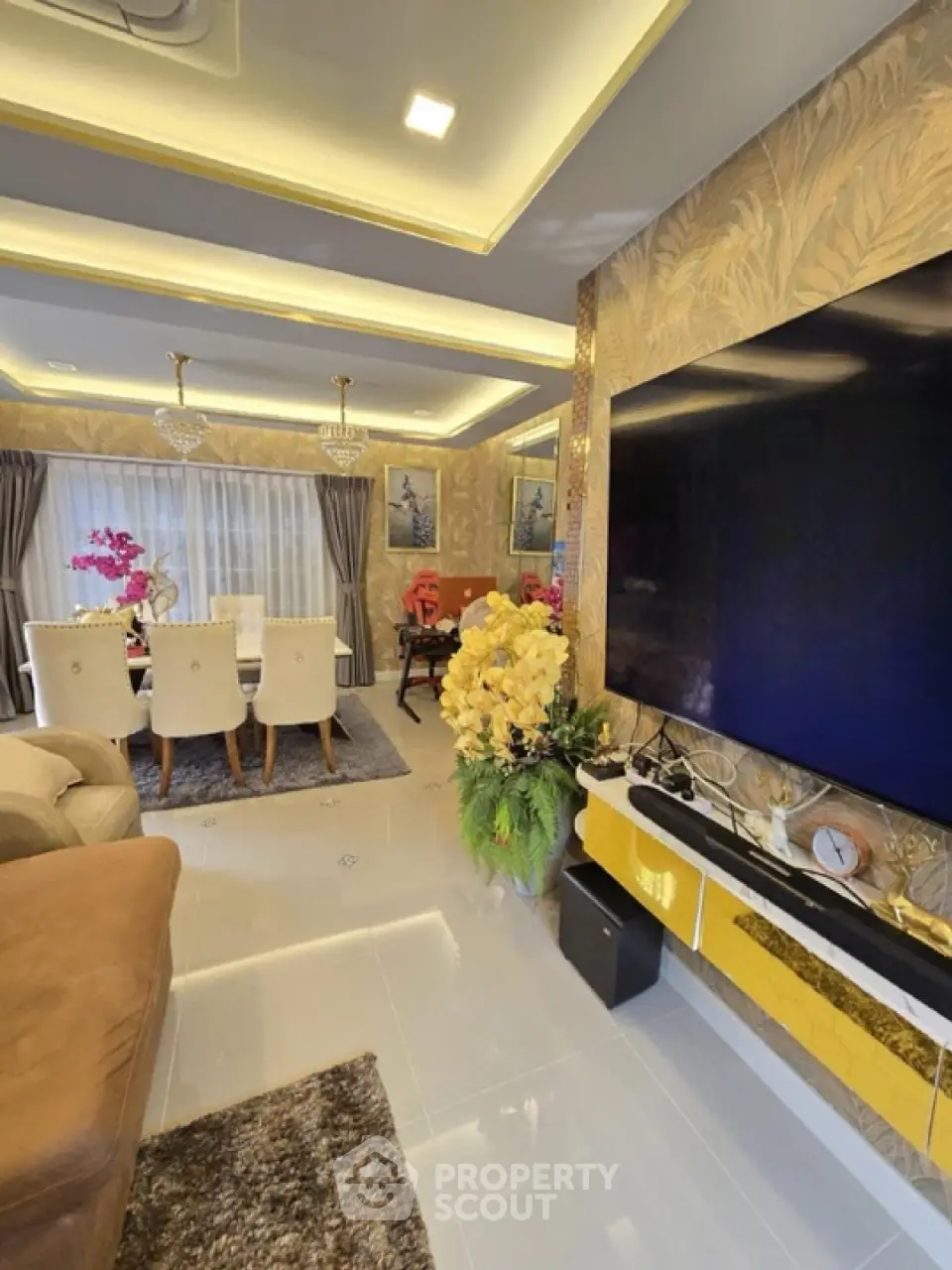 Luxurious living room with elegant decor, large TV, and stylish dining area, perfect for modern living.