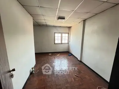 Spacious empty room with wooden flooring and window, ideal for customization.