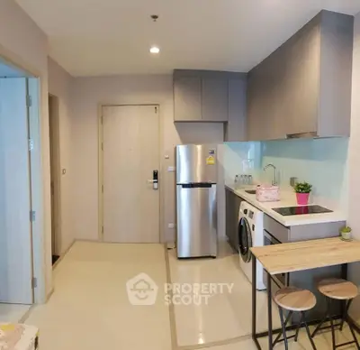 Modern compact kitchen with stainless steel appliances and breakfast bar in cozy apartment.