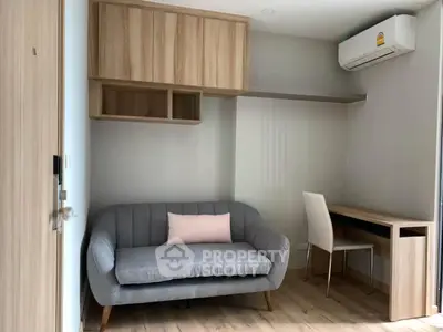 Modern living room with stylish sofa and workspace, featuring wooden flooring and air conditioning.