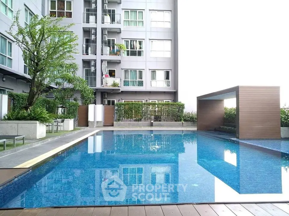 Modern apartment building with a luxurious outdoor pool and lush greenery.