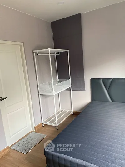 Minimalist bedroom with modern bed and storage rack, perfect for urban living.