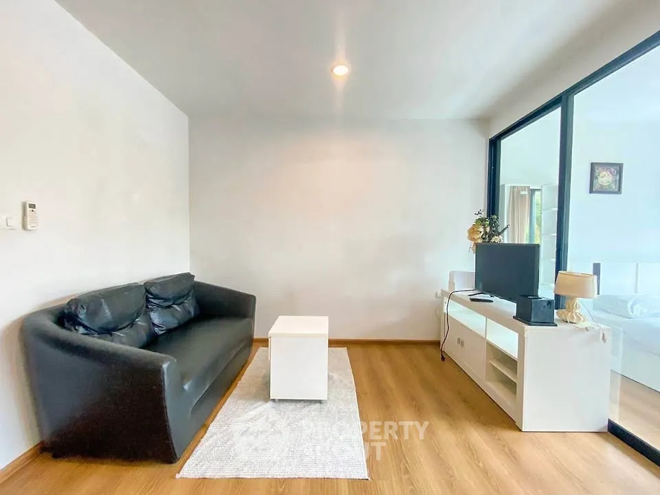 Modern living room with sleek black sofa and large window for natural light.