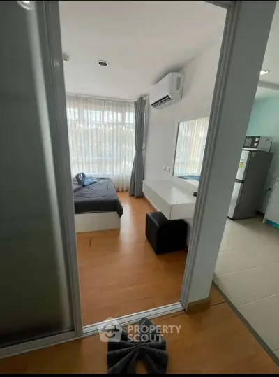 Modern bedroom with wooden flooring, large window, and air conditioning in a cozy apartment.
