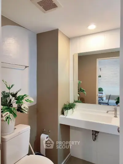 Modern bathroom with sleek fixtures and stylish decor, featuring a large mirror and elegant sink.