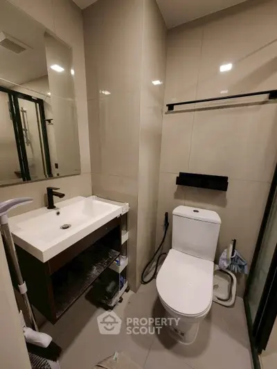 Modern bathroom with sleek fixtures and neutral tiles, featuring a contemporary sink and toilet.