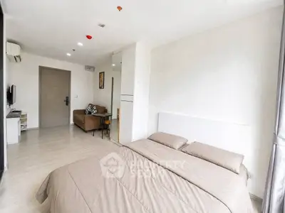 Modern bedroom with minimalist decor and cozy seating area in a stylish apartment.